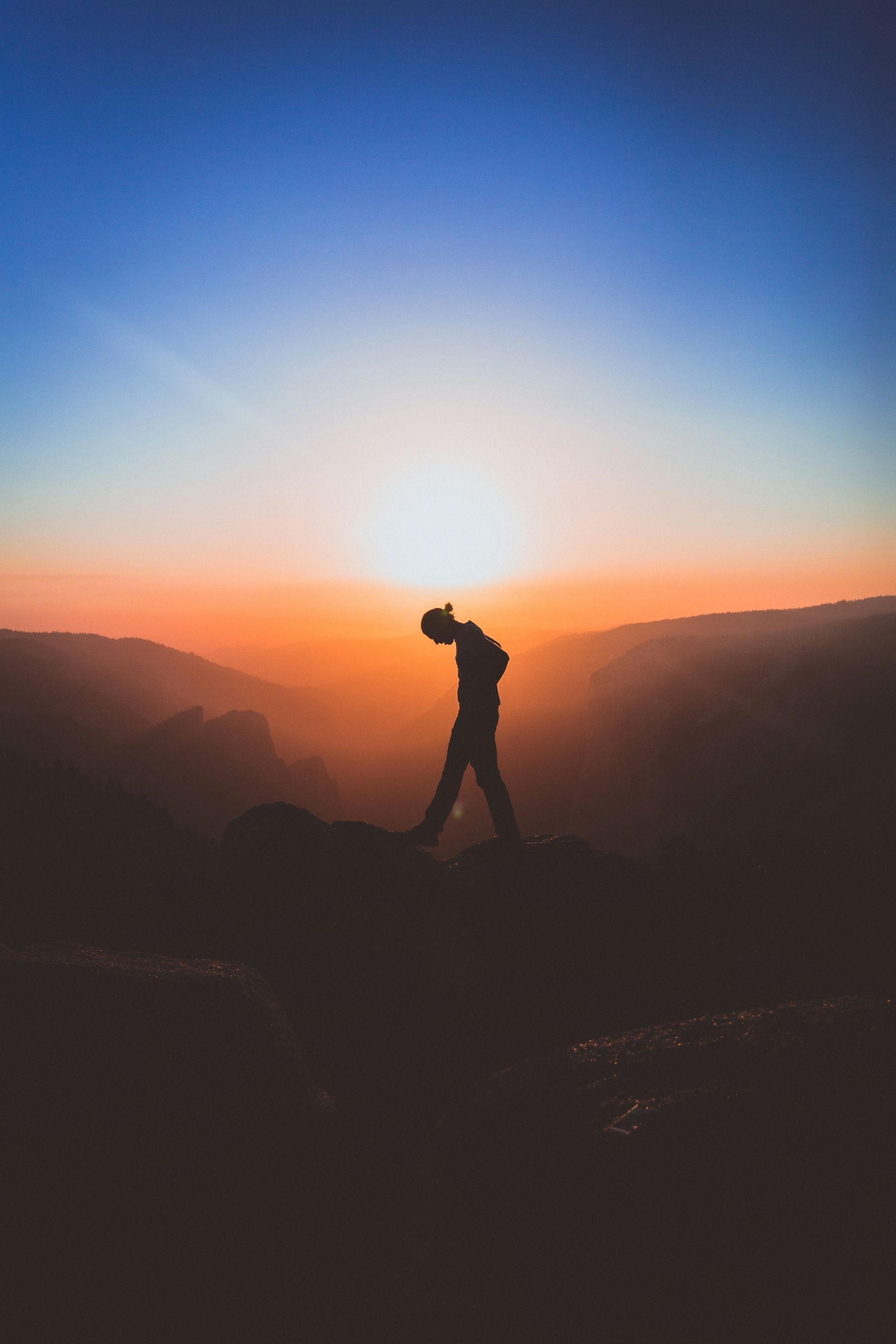 A silhouette of a hiker against a stunning mountain backdrop.